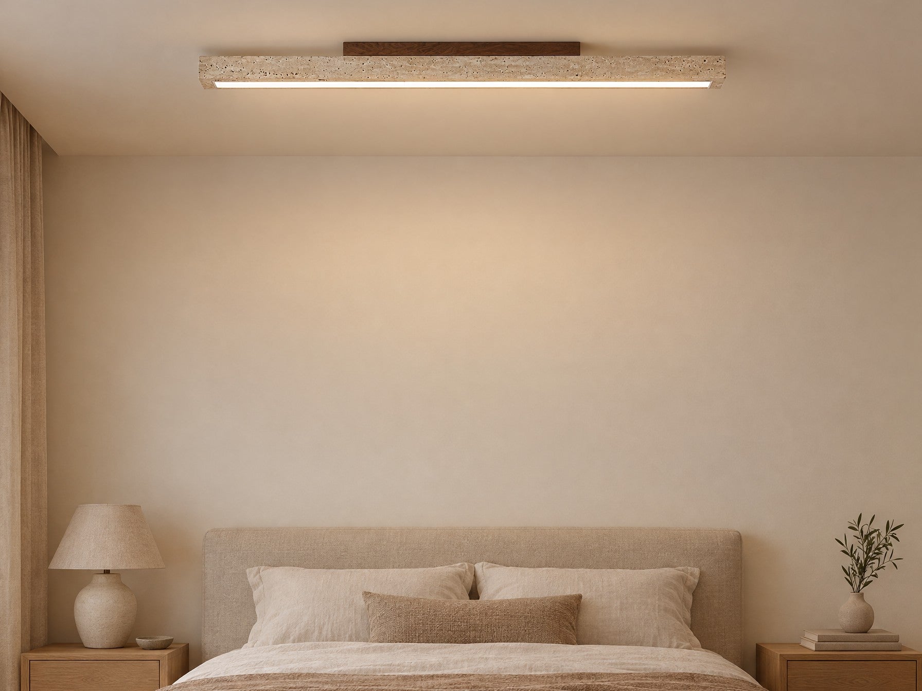 Travellin Ceiling Light, travertine bar with dark walnut mount, lit on a bedroom ceiling above a linen bed