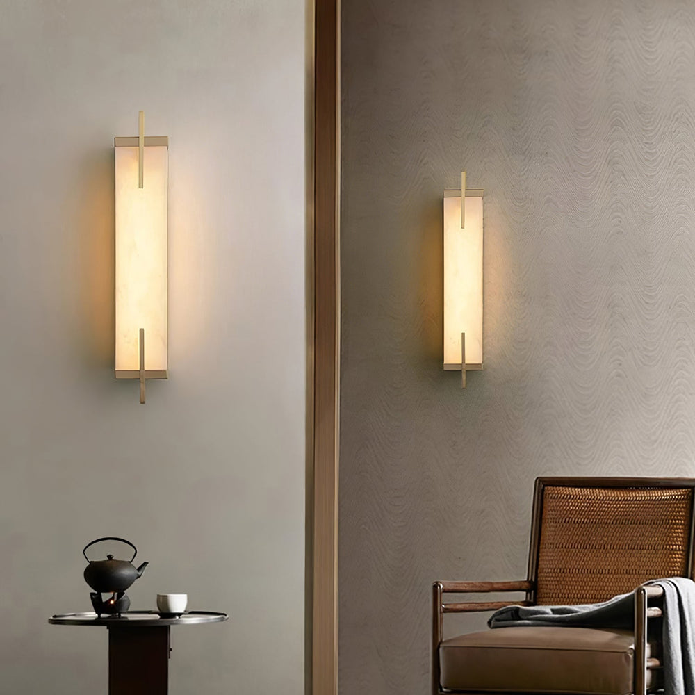 Two slim illuminated Serrane alabaster sconces on a wall above a chair