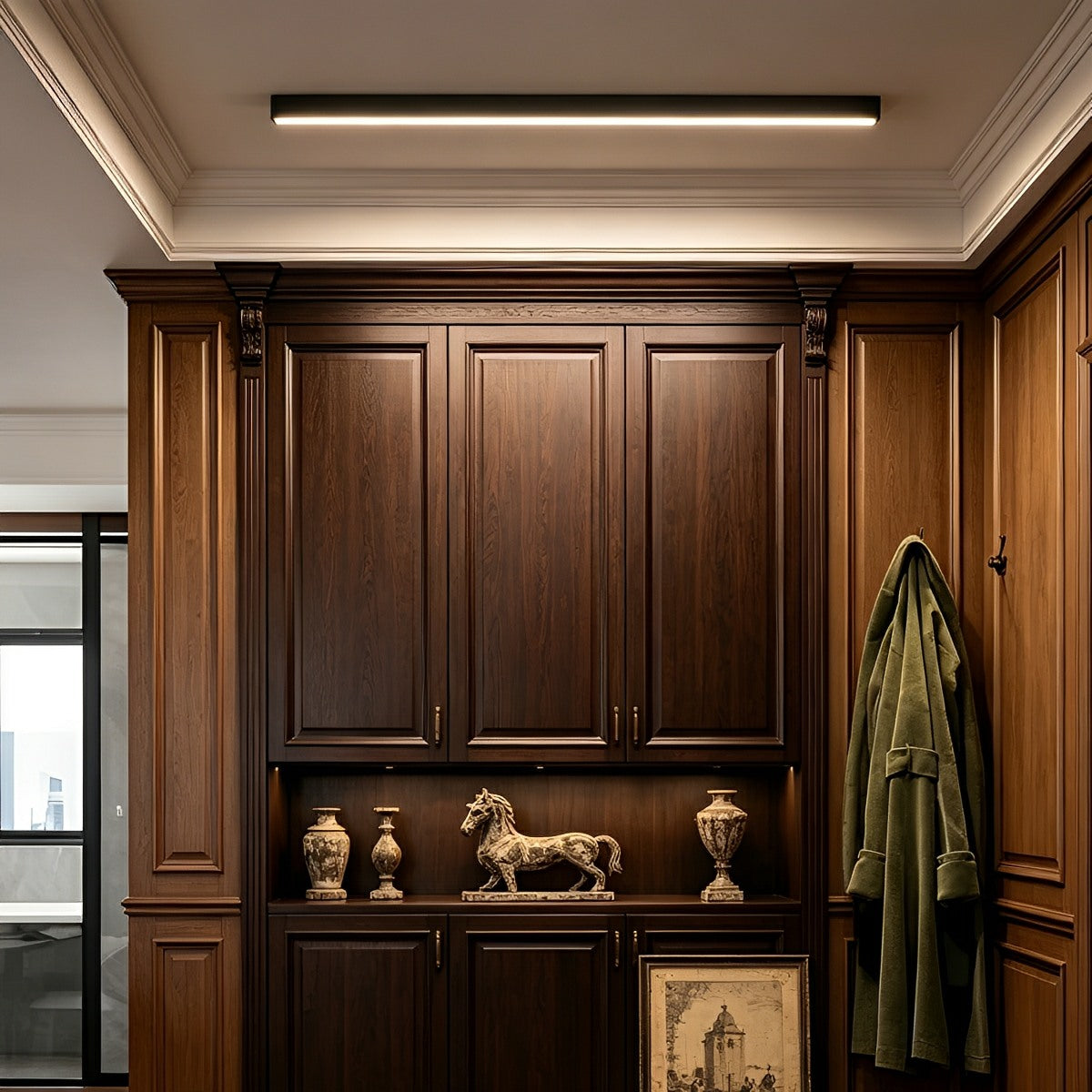 Slim linear LED ceiling light with a black body, fitted along a ceiling above dark wooden cabinets.