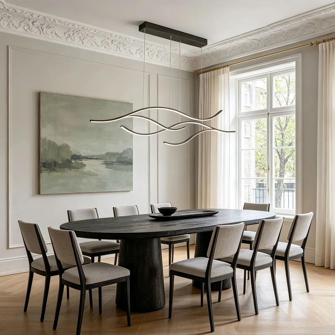 Linear pendant light made of wavy black LED bars hung from a slim rectangular canopy above an oval dining table in a panelled room.