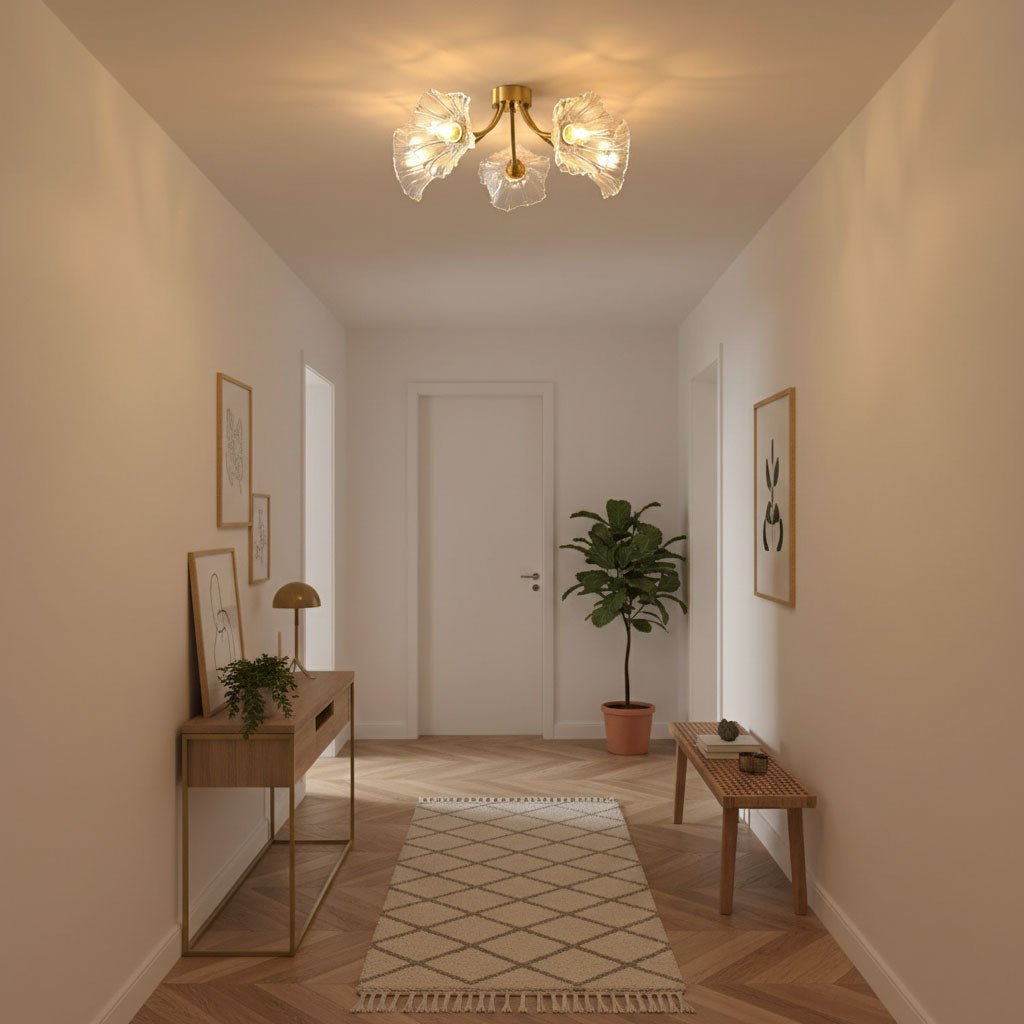 Flush-mount ceiling lamp with curved brass arms holding clear ribbed flower-shaped glass shades lit on a hallway ceiling.