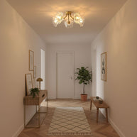 Flush-mount ceiling lamp with curved brass arms holding clear ribbed flower-shaped glass shades lit on a hallway ceiling.