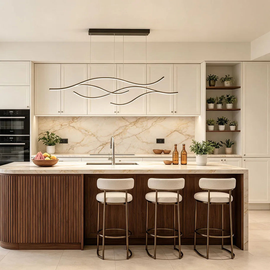 Linear pendant light made of wavy black LED bars hung from a slim rectangular canopy above a kitchen island with cream cabinets.