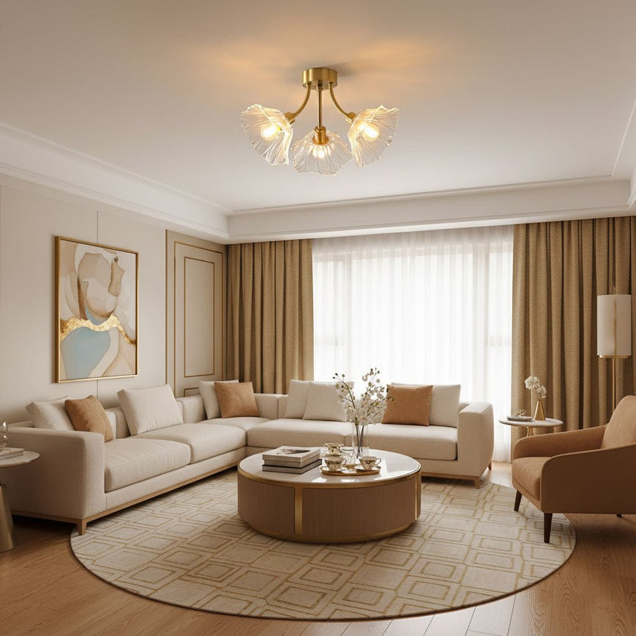 Flush-mount ceiling lamp with curved brass arms holding clear ribbed flower-shaped glass shades lit on a ceiling above a living room.