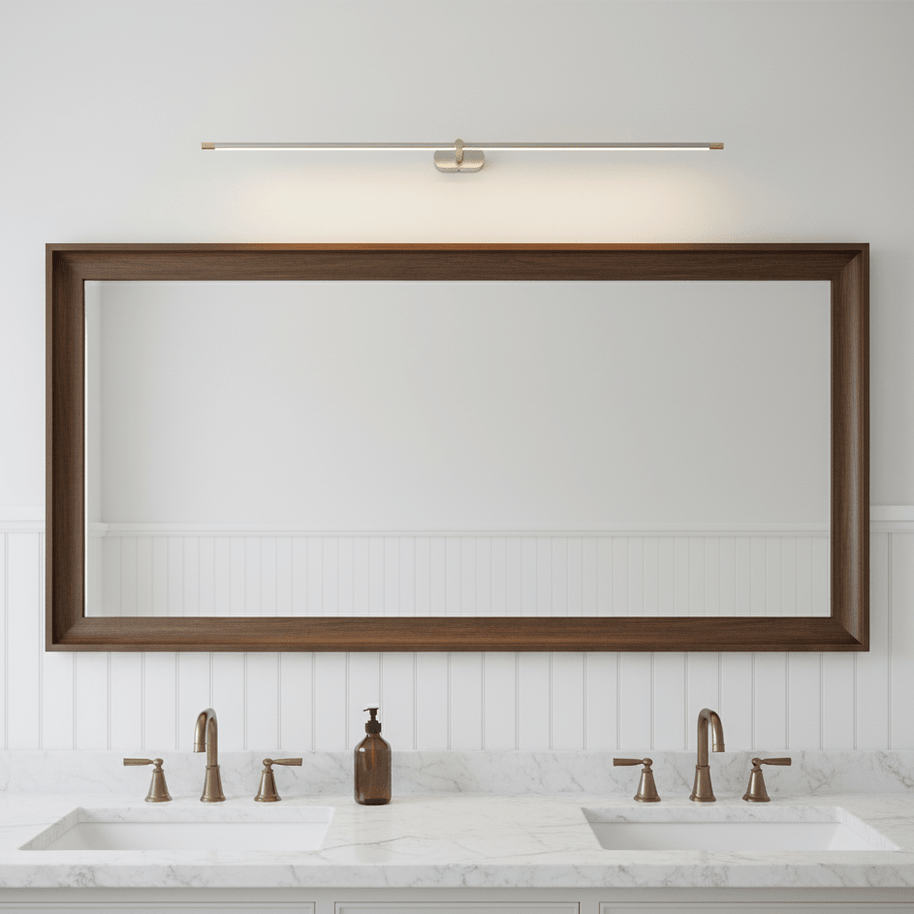 Brushed nickel and gold slim linear LED wall light lit above a timber-framed mirror over a double vanity