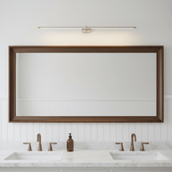 Brushed nickel and gold slim linear LED wall light lit above a timber-framed mirror over a double vanity