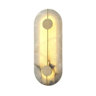 Wall light with a tall rounded alabaster panel, a slim brass rod and two brass discs lit on a white background.