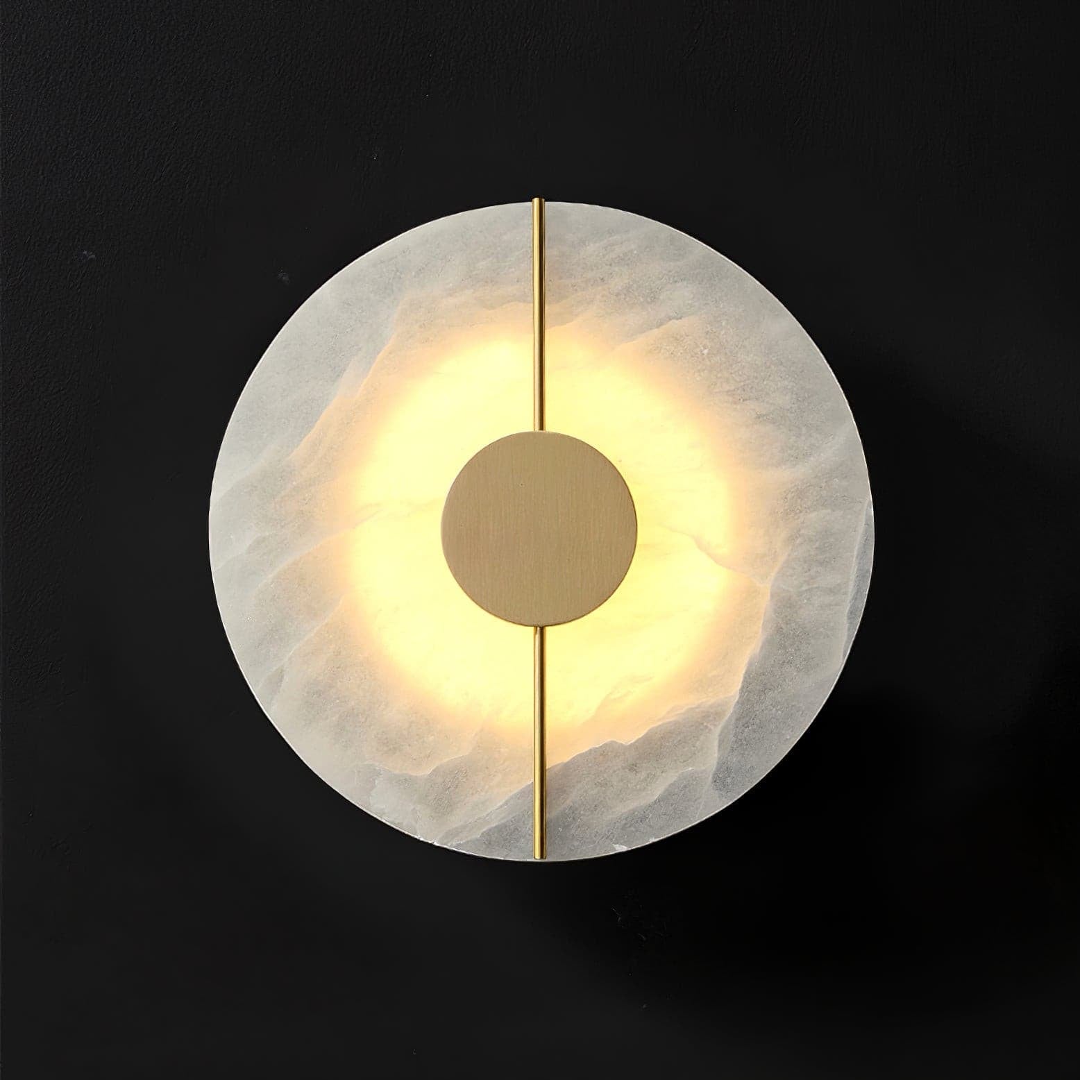 Wall light with a round veined alabaster disc, a slim brass rod and a brass centre disc lit on a dark background.