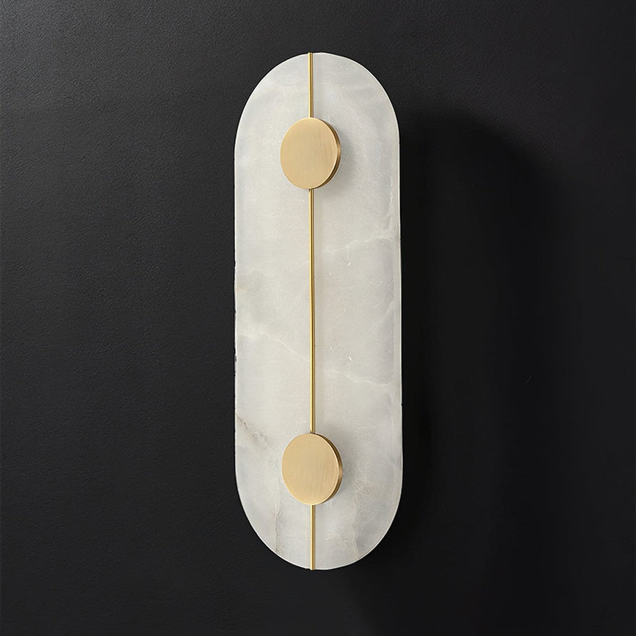 Wall light with a tall rounded alabaster panel, a slim brass rod and two brass discs, unlit, on a dark background.
