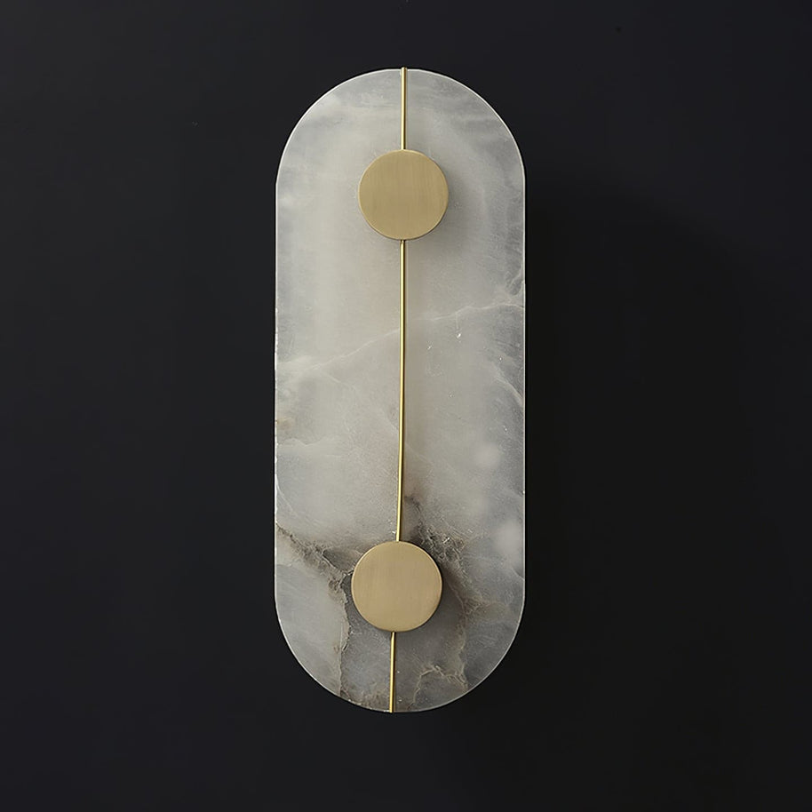 Wall light with a tall rounded alabaster panel, a slim brass rod and two brass discs, unlit, on a dark background.