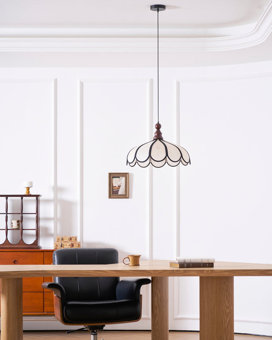 Pendant light with a scalloped beige shade, dark ribs and a turned walnut-coloured wooden top hanging in a panelled room above a wooden desk.