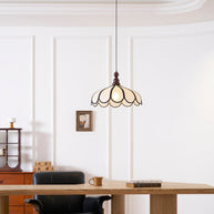 Pendant light with a scalloped beige shade, dark ribs and a turned walnut-coloured wooden top lit in a panelled room above a desk.