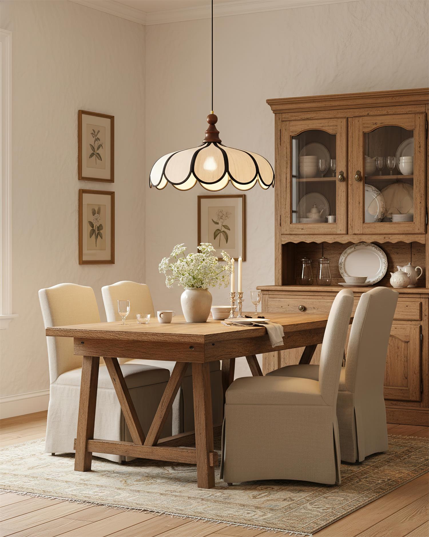 Pendant light with a scalloped beige shade, dark ribs and a turned walnut-coloured wooden top lit above a wooden dining table beside a dresser.