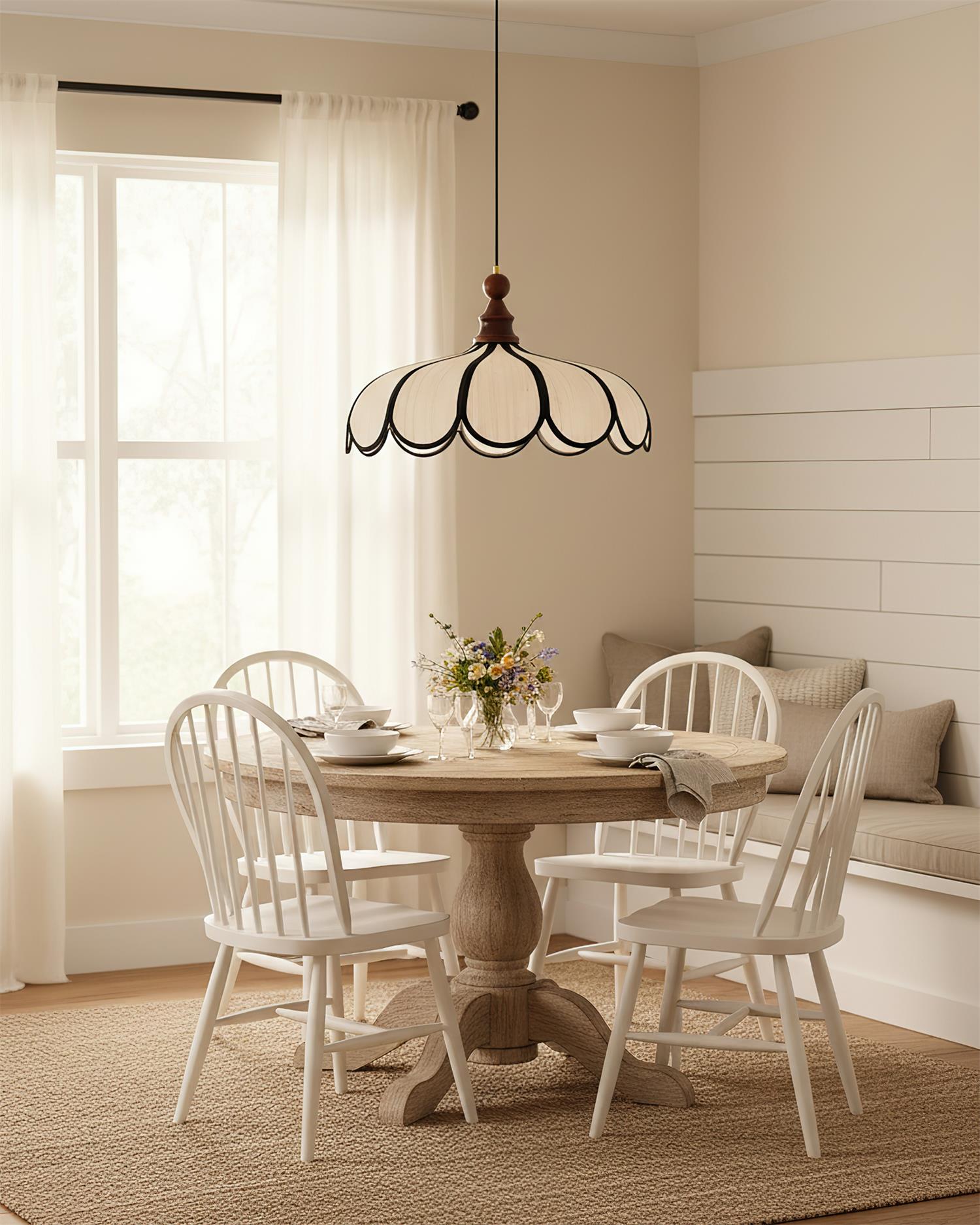 Pendant light with a scalloped beige shade, dark ribs and a turned walnut-coloured wooden top above a round dining table with white chairs.