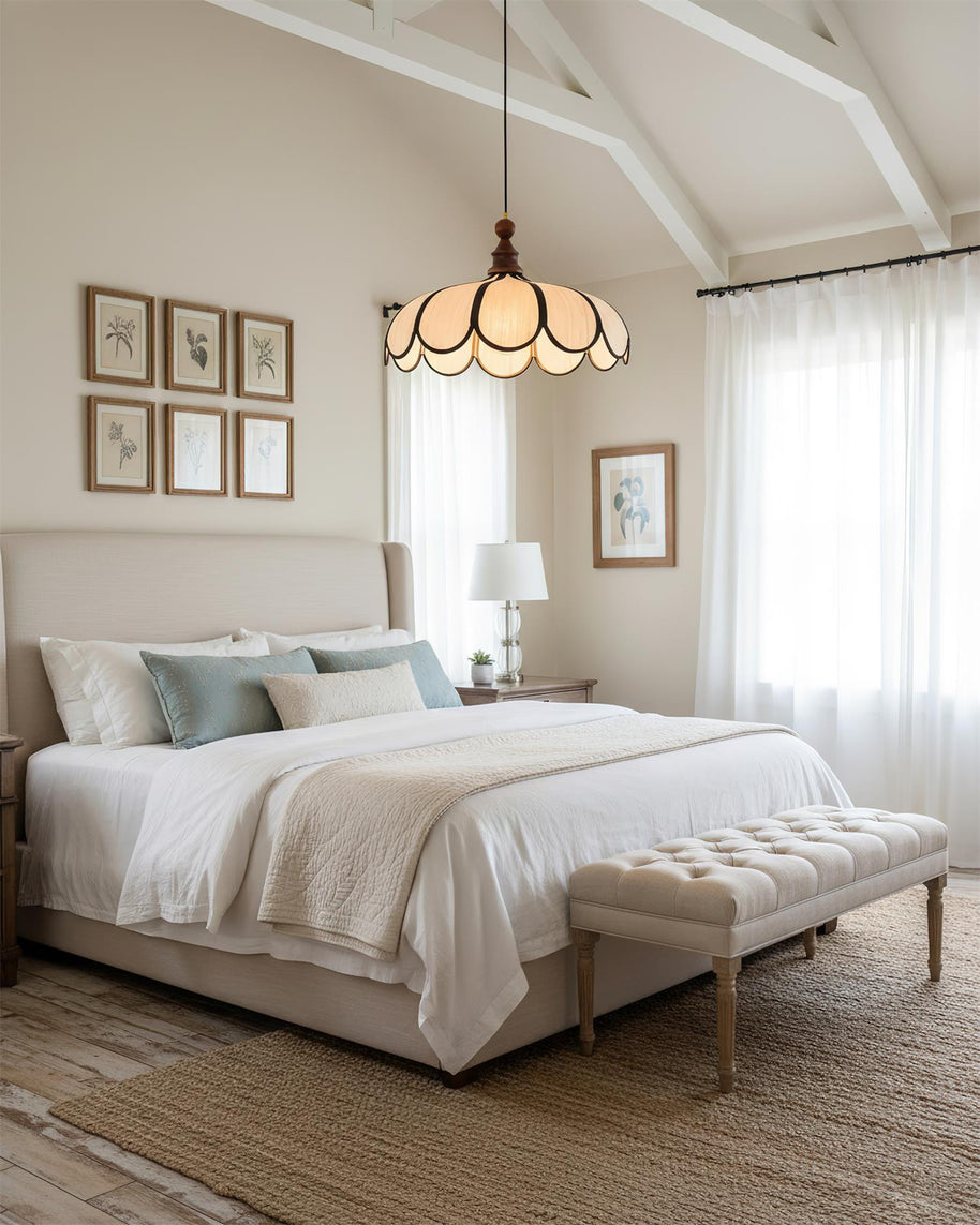 Pendant light with a scalloped beige shade, dark ribs and a turned walnut-coloured wooden top lit above a bed in a room with a sloped ceiling.