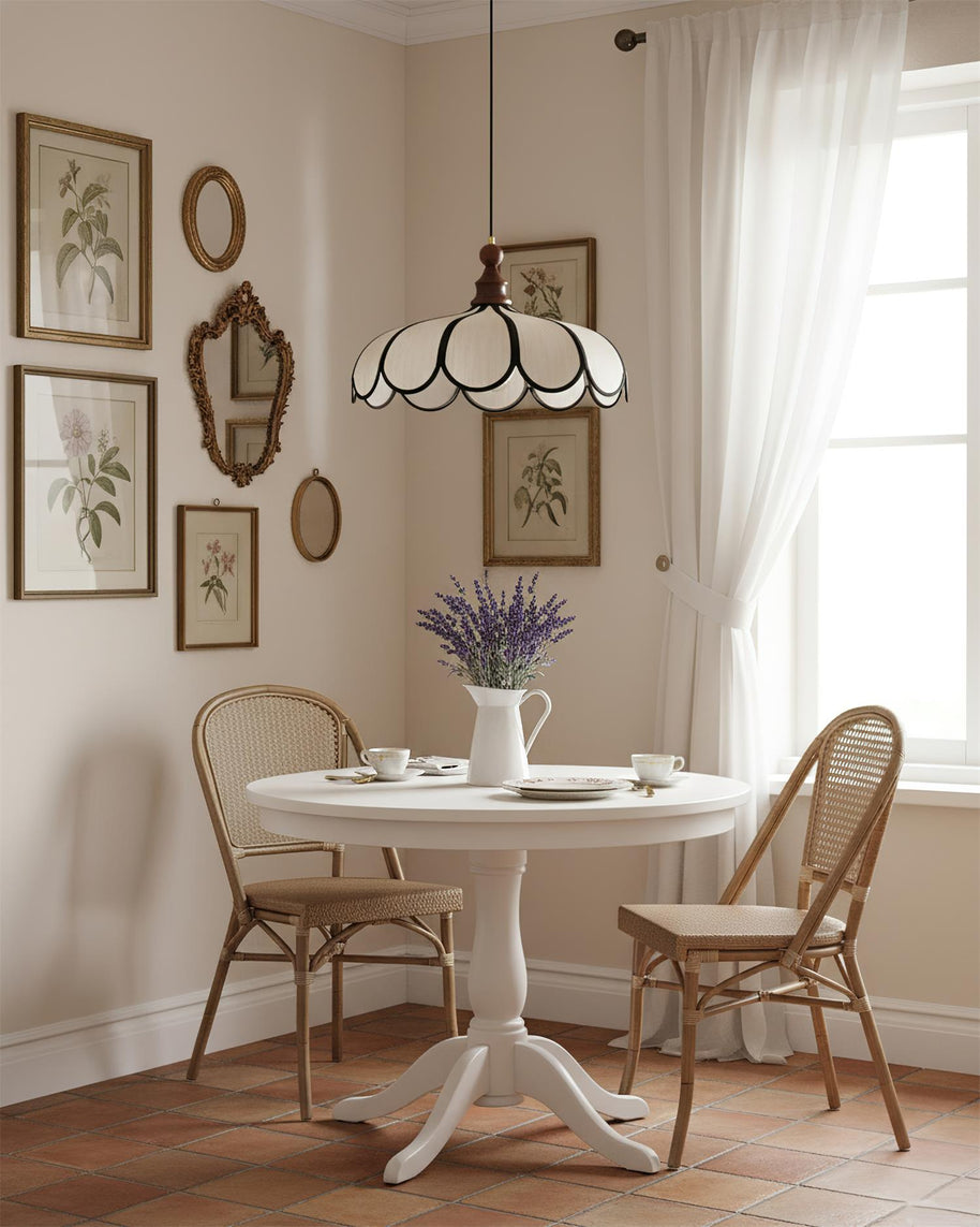 Pendant light with a scalloped beige shade, dark ribs and a turned walnut-coloured wooden top above a small round table with two cane chairs.