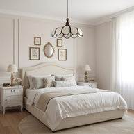 Pendant light with a scalloped beige shade, dark ribs and a turned walnut-coloured wooden top above a bed in a bedroom with framed prints and a mirror.