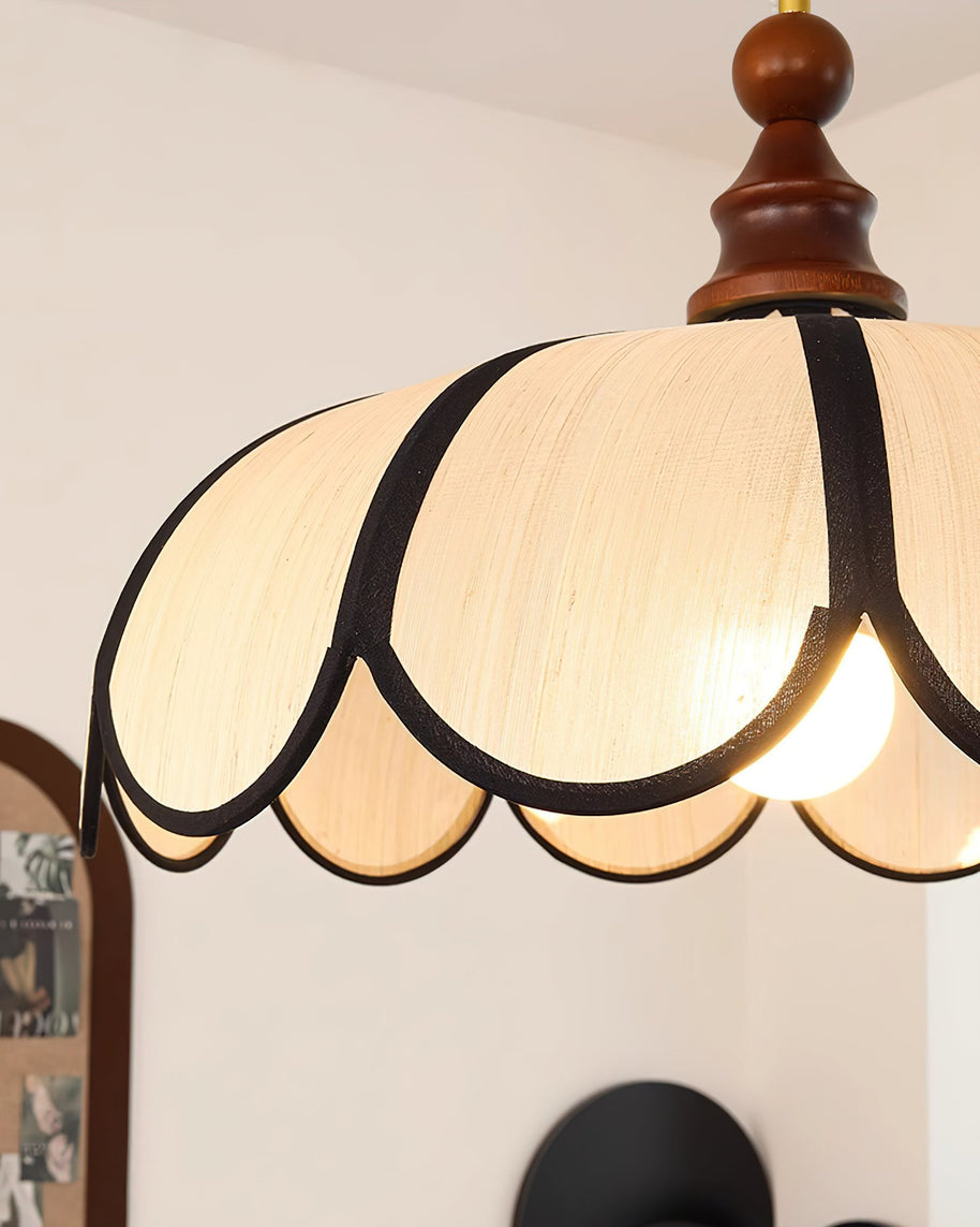 Close view of the shade top and the turned walnut-coloured finial, light on.