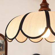 Close view of the shade top and the turned walnut-coloured finial, light on.