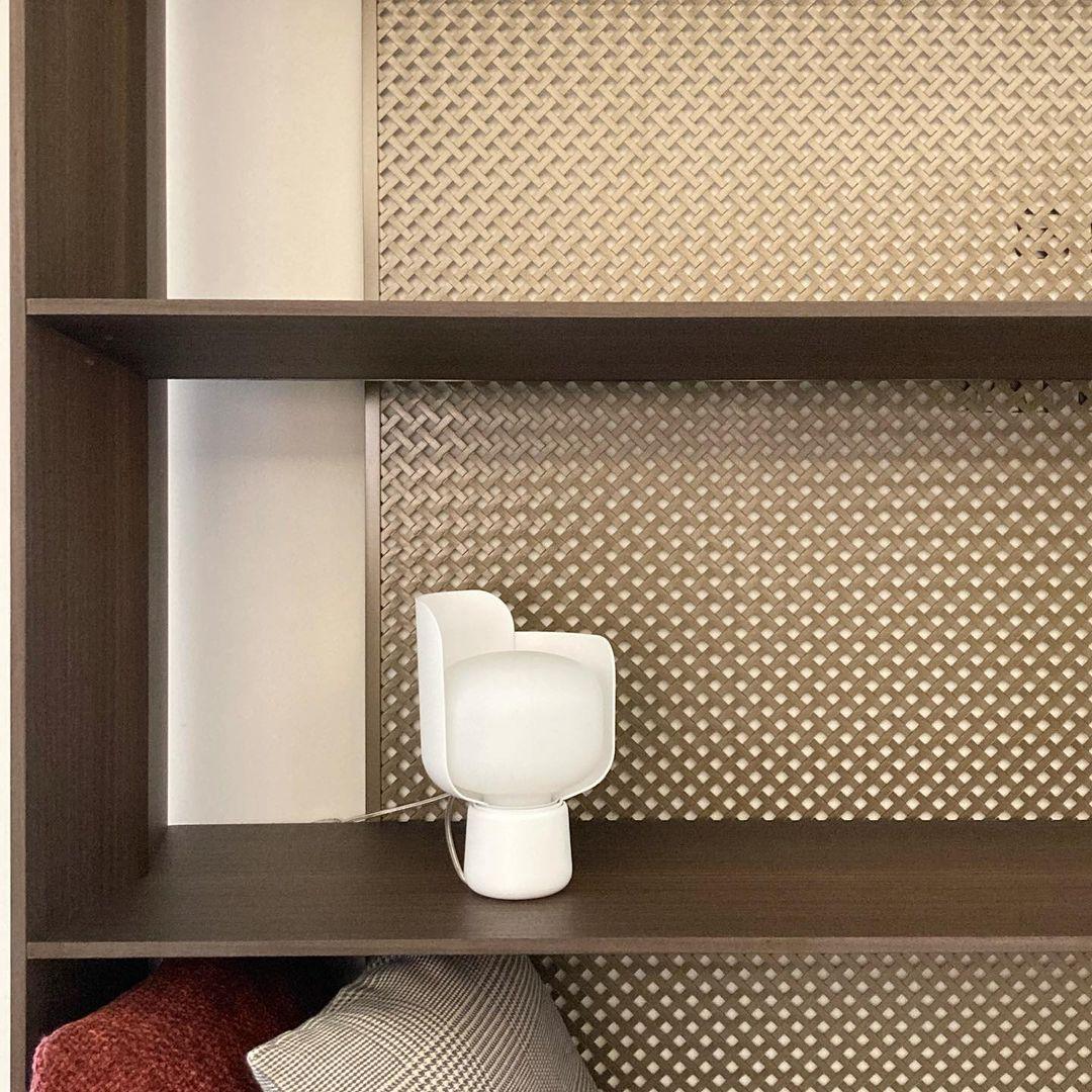 Pethella Table Lamp in white on a dark wood shelf