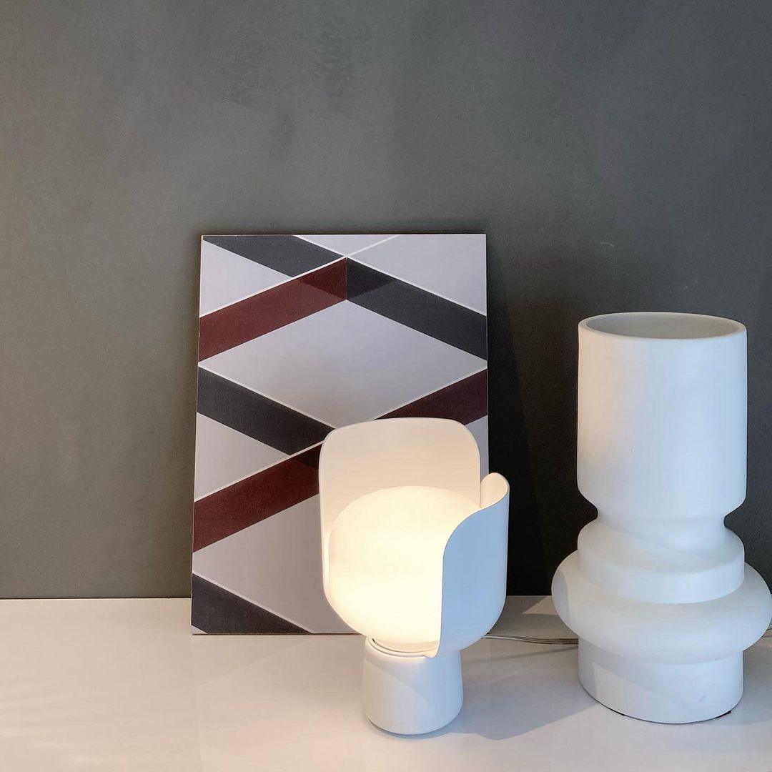 Pethella Table Lamp in white, lit beside a white vase