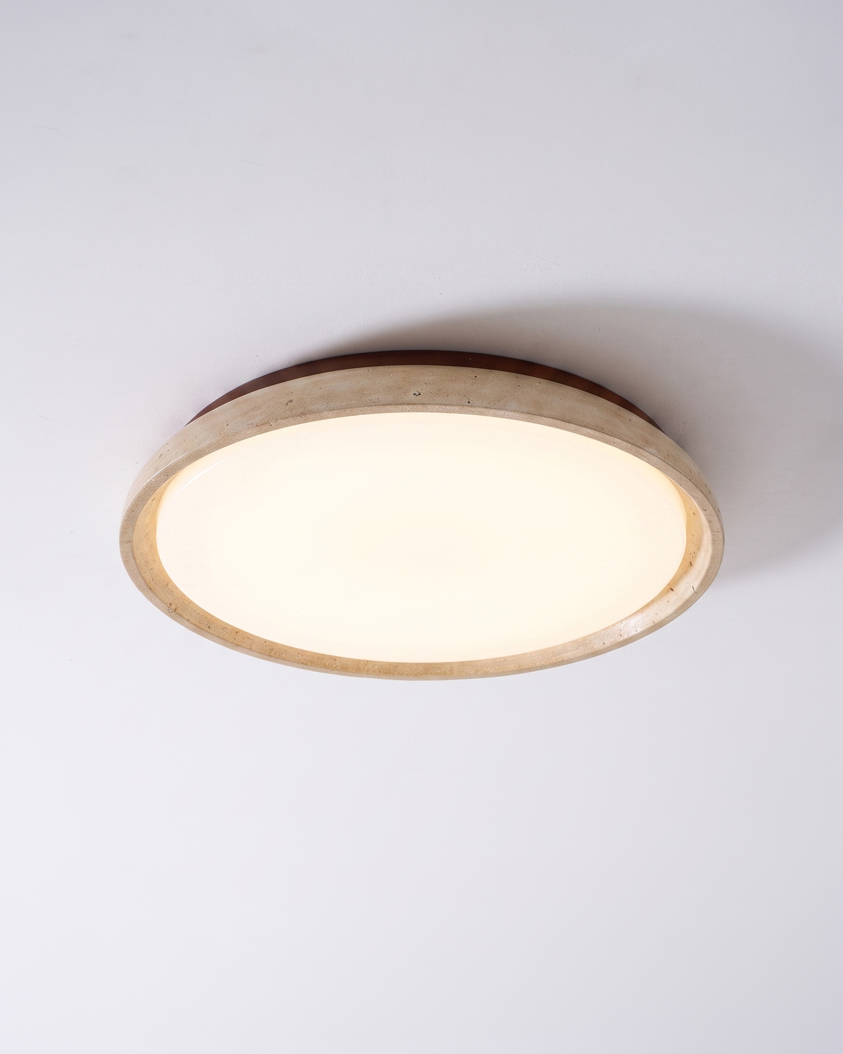 Pietra Walnut Travertine Ceiling Light in walnut colour and beige, shown lit with warm white light.