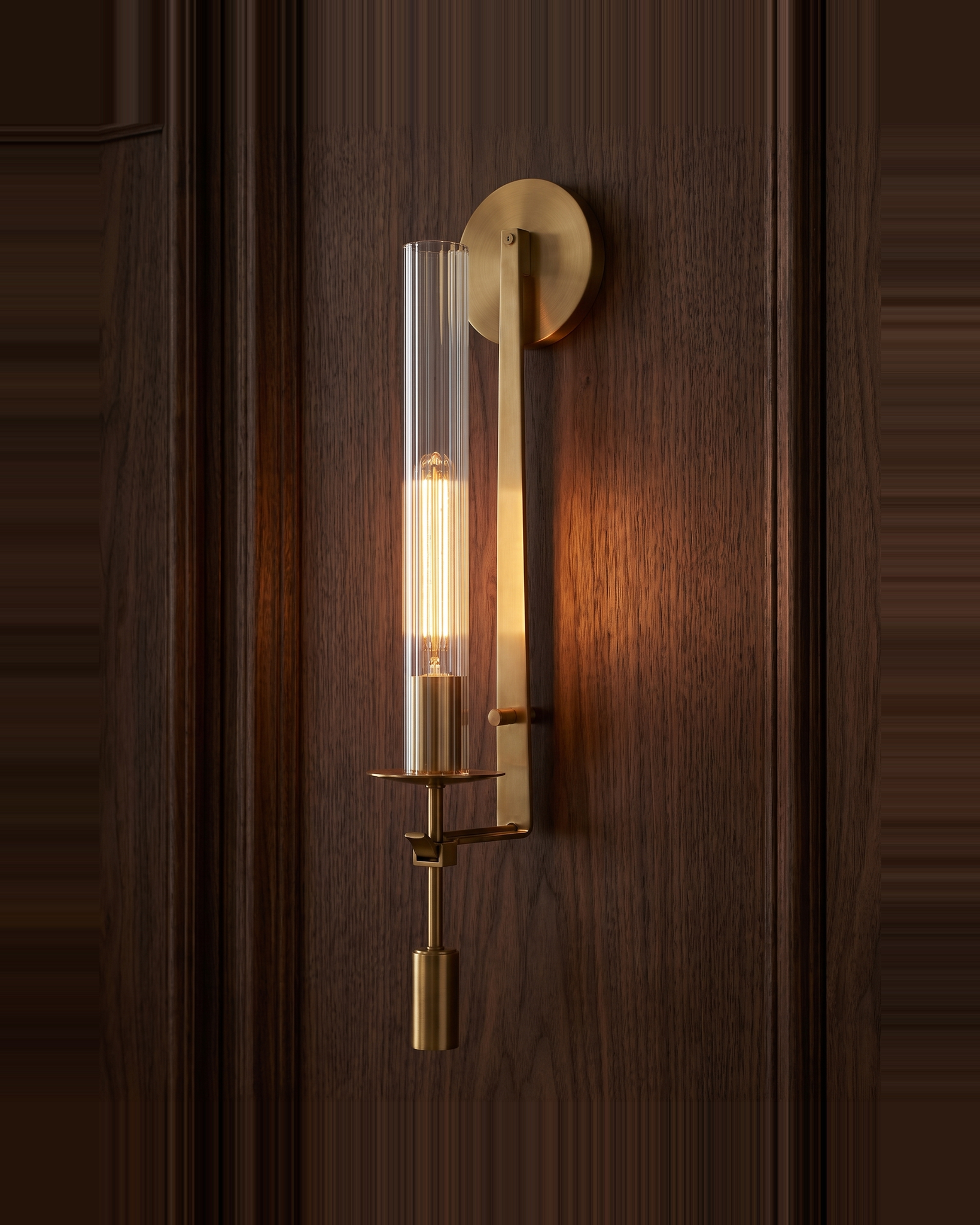 Valenne Ribbed Glass Wall Sconce lit against dark walnut panelling
