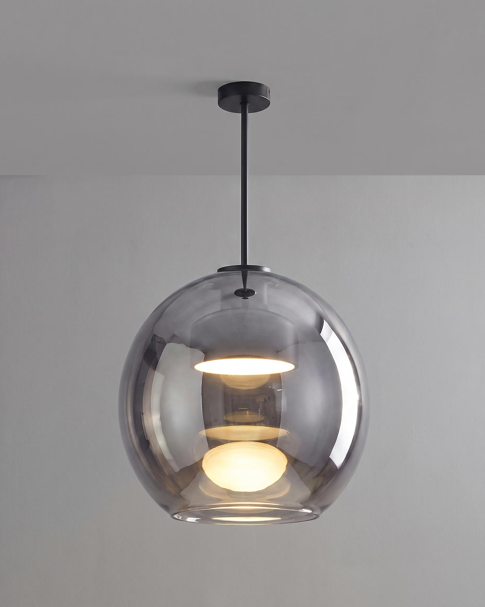 Comvilo Metro Sphere Glass Pendant Lamp in black metal and smoke-grey glass, shown lit with warm light.