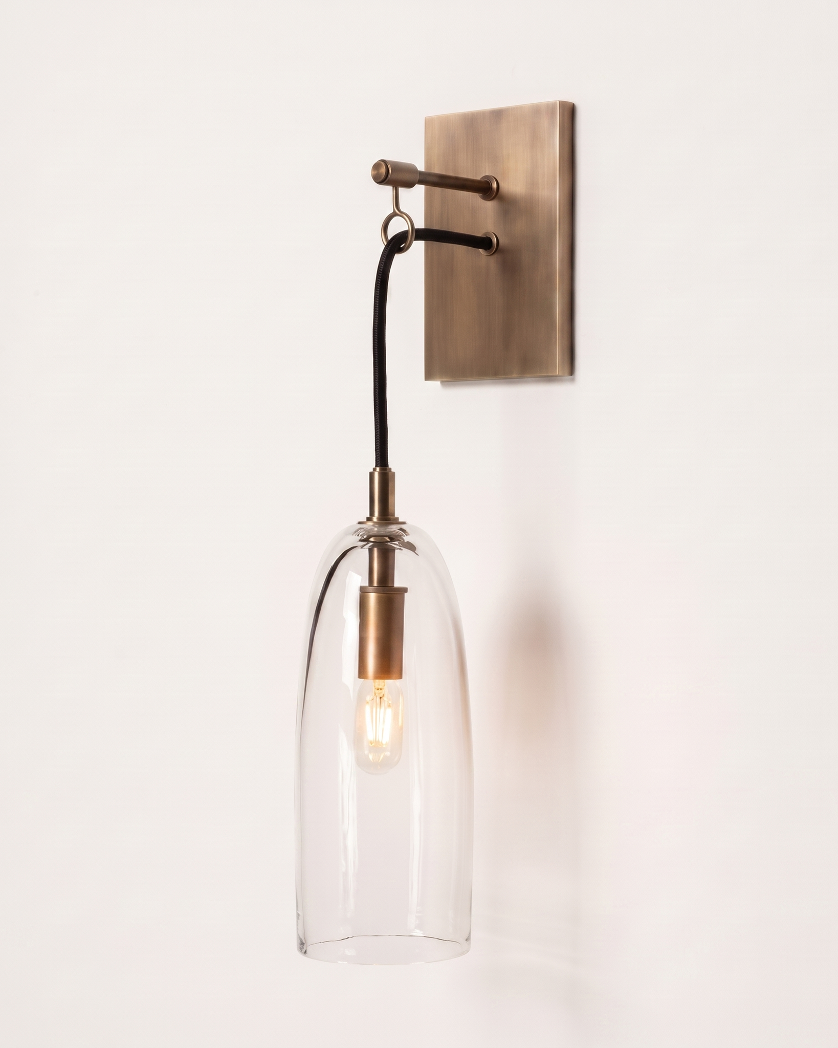 Comvilo Lure Wall Lamp in brass and clear, installed in a plain interior.