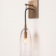 Comvilo Lure Wall Lamp in brass and clear, installed in a plain interior.