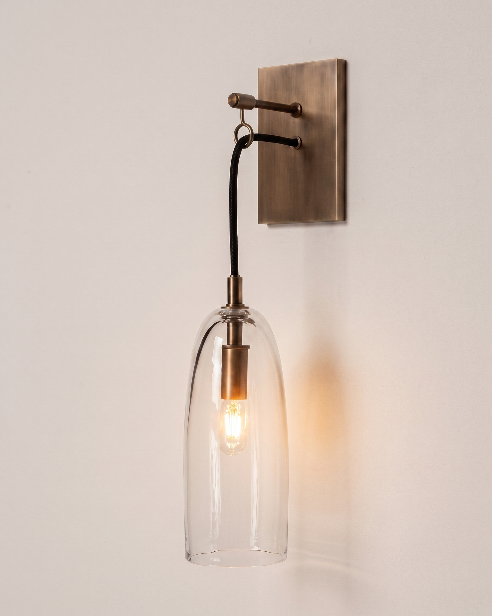Comvilo Lure Wall Lamp in brass and clear, shown lit.