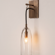 Comvilo Lure Wall Lamp in brass and clear, shown lit.