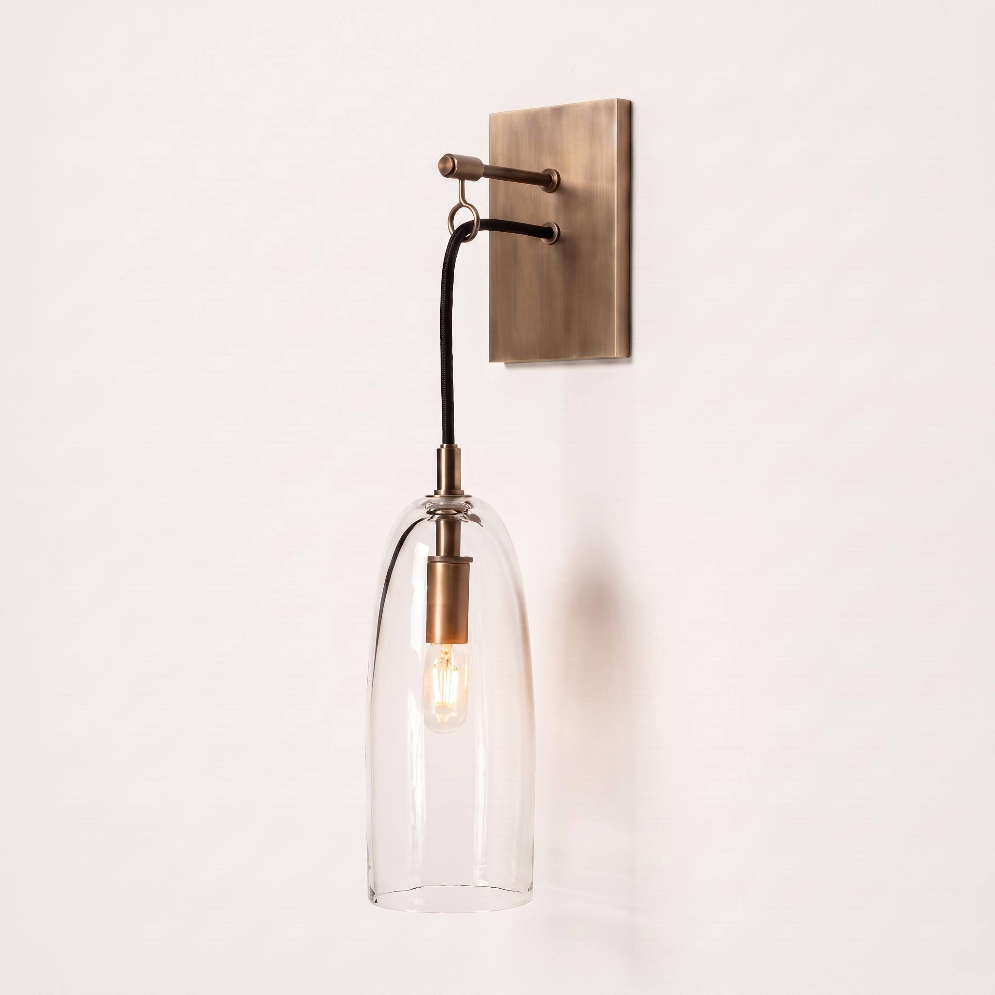 Comvilo Lure Wall Lamp in brass and clear, complete, on a plain studio background.