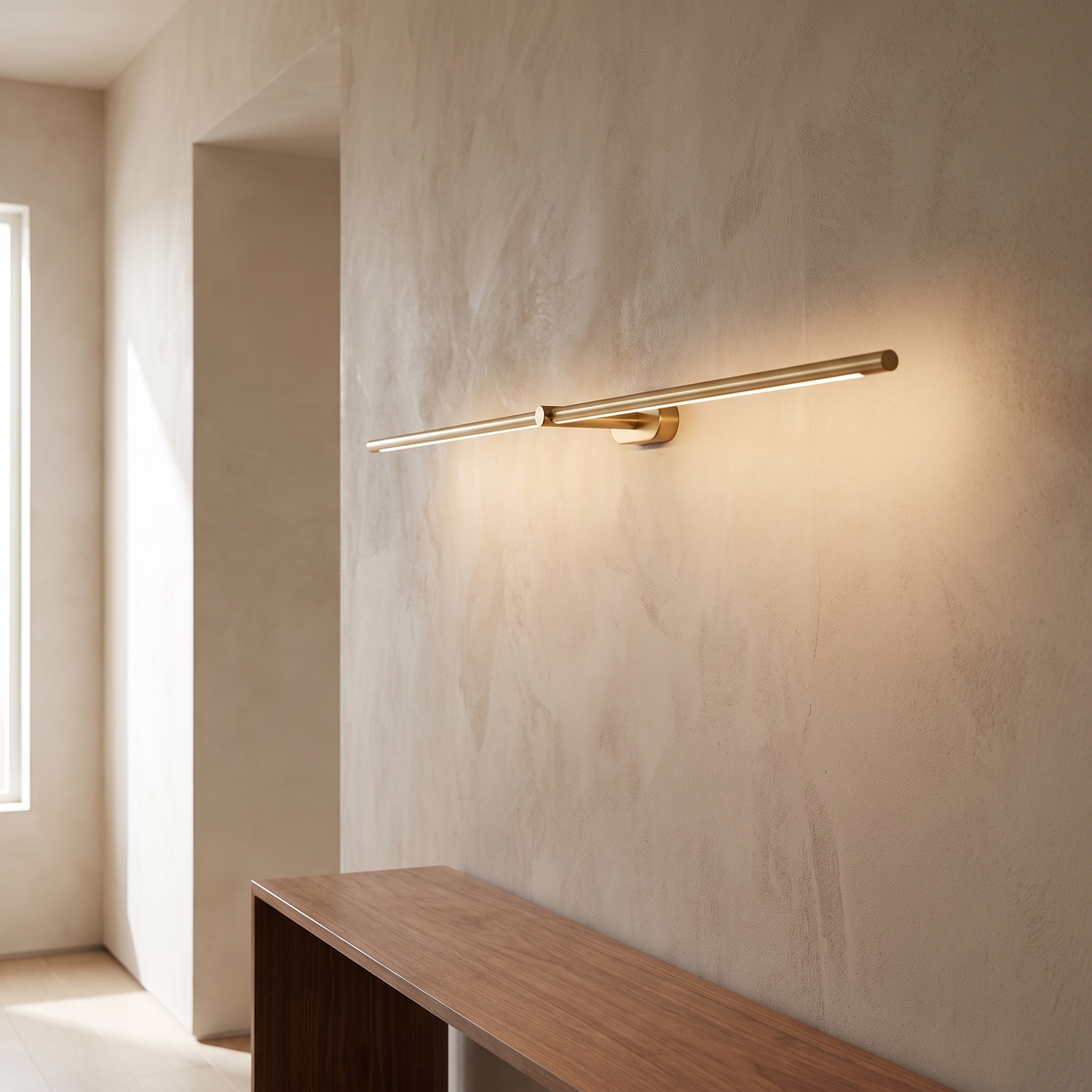 Kady Linear Rechargeable Wall Lamp in gold, mounted horizontally on a plaster hallway wall above a walnut console