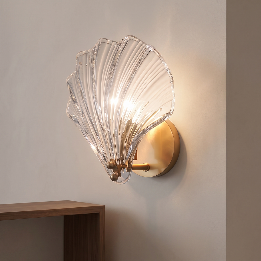 Brass shell-shaped wall light with a clear ribbed glass shade.