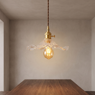 Clear flower-shaped glass pendant light with brass hardware.