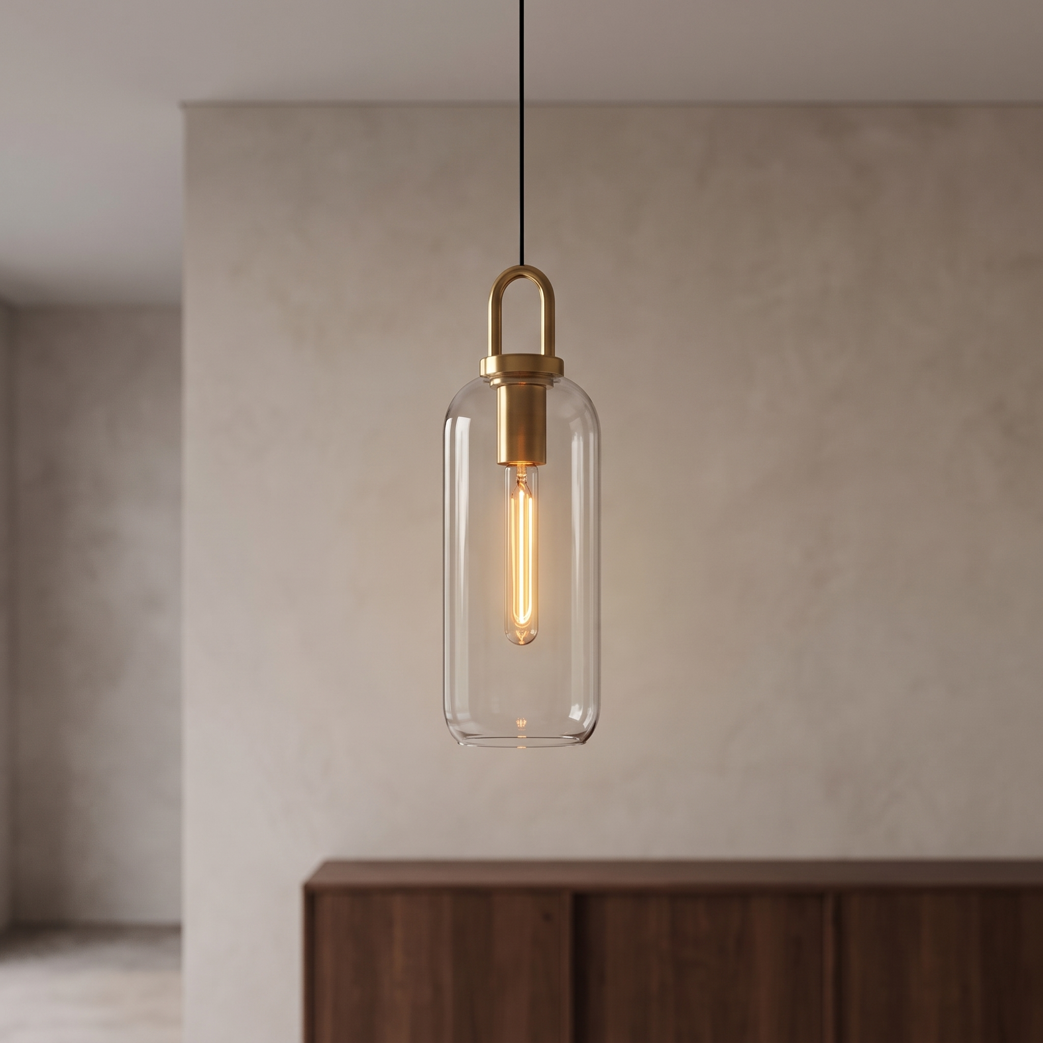 Clear cylindrical glass pendant light with brass hardware.