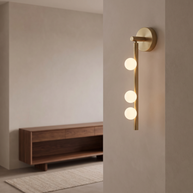 Brass three-globe wall light with white glass shades.