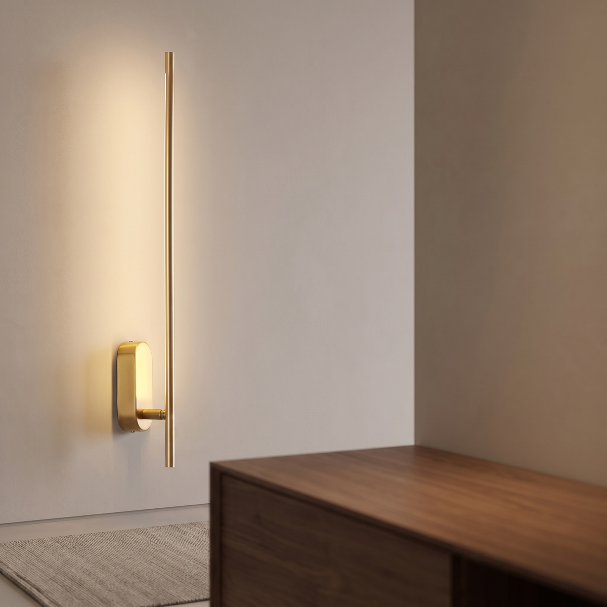 Slim brass vertical wall sconce casting warm light
