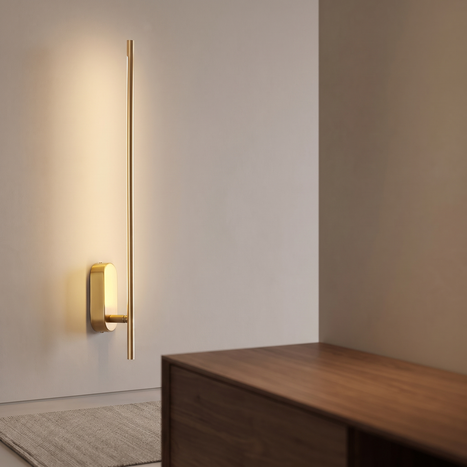 Slim brass vertical wall sconce casting warm light.