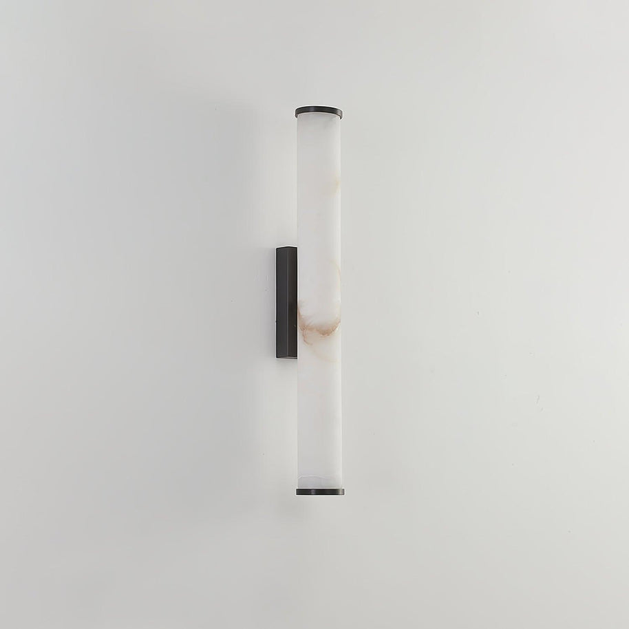 Wall lamp with a long pale veined alabaster tube and a black bracket, unlit, on a plain pale wall.