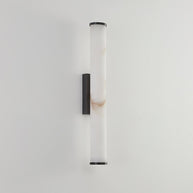 Wall lamp with a long pale veined alabaster tube and a black bracket, unlit, on a white wall.