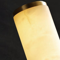 Close view of the brass-coloured end cap and the veined alabaster tube, lit.