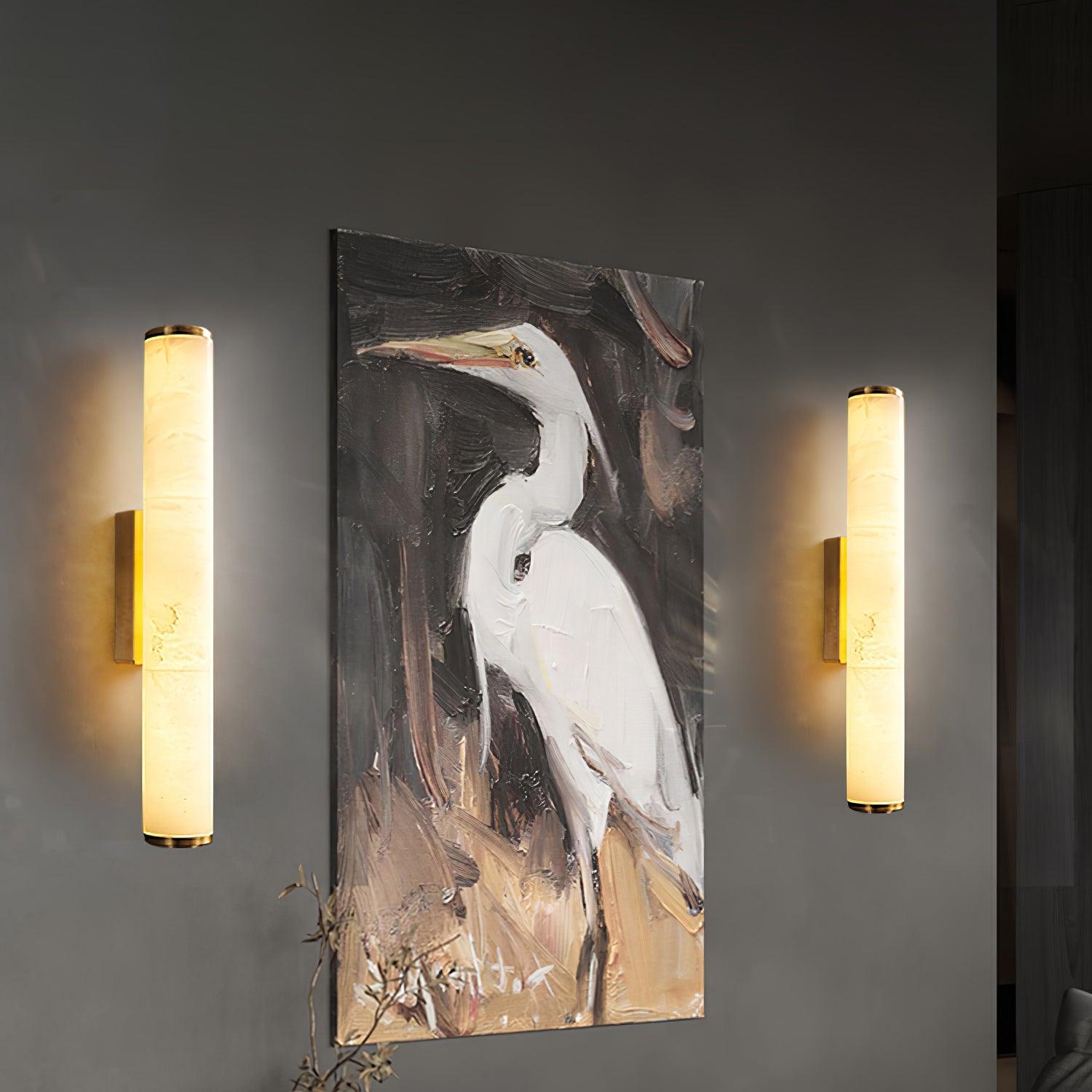 Two of the wall lamps lit either side of a large painting of a heron.