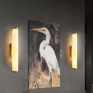 Two of the wall lamps lit either side of a large painting of a heron.