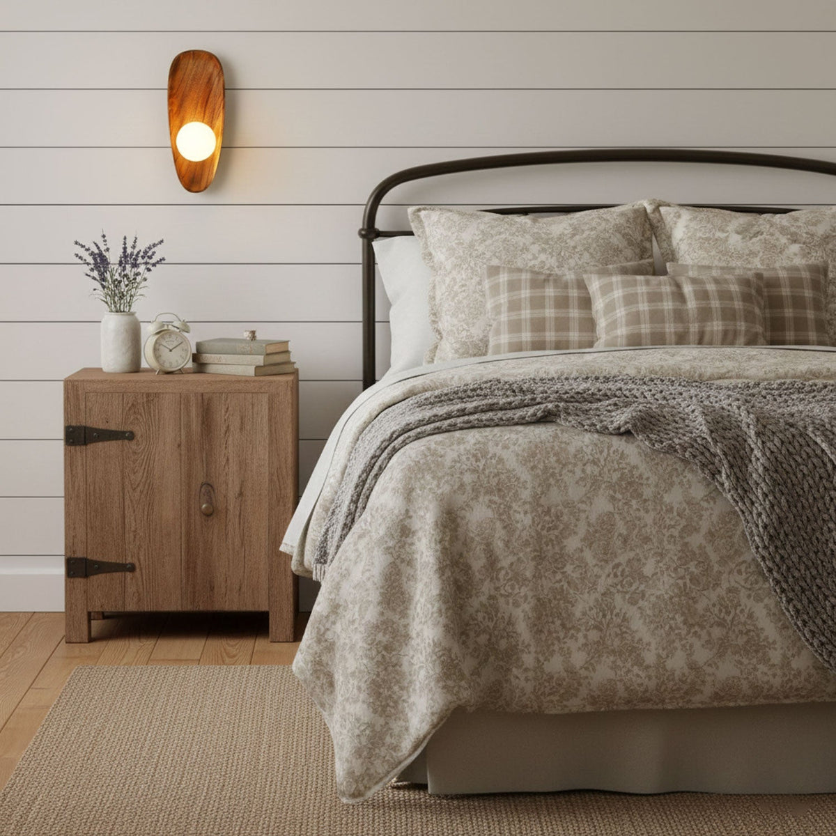 Wall lamp with a shaped walnut-coloured wooden backplate and a white glass globe lit on a white boarded wall above a bedside cabinet.