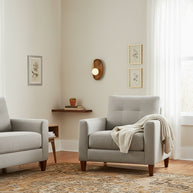 Wall lamp with a shaped walnut-coloured wooden backplate and a white glass globe on a wall between framed prints in a sitting room.
