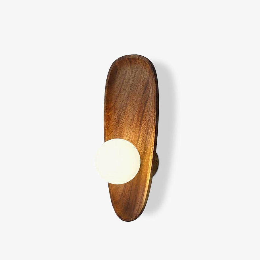 Wall lamp with a shaped walnut-coloured wooden backplate and a white glass globe, narrow upright shape, seen at an angle on a white background.