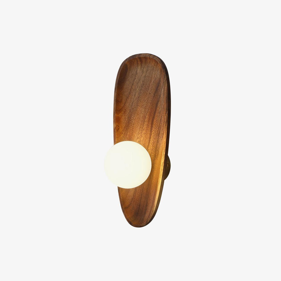 Wall lamp with a shaped wooden backplate and a white glass globe, lit, shown on a plain background with the wood grain catching the light.