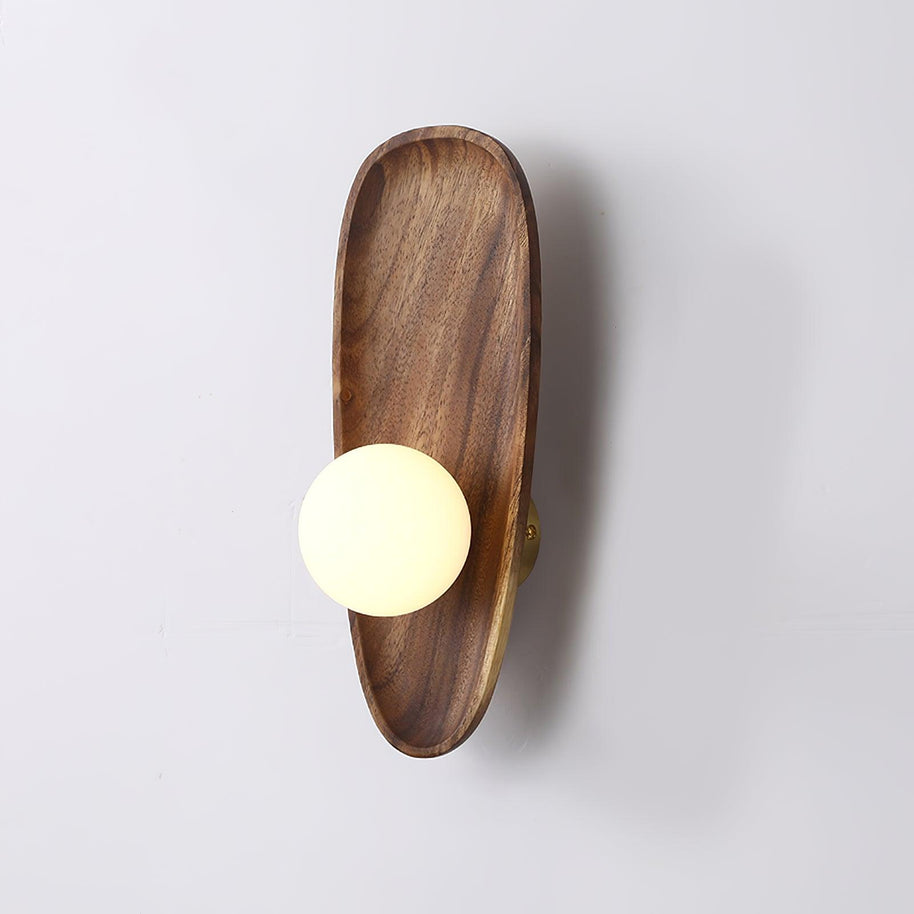 Wall lamp with a shaped walnut-coloured wooden backplate and a white glass globe, narrow upright shape, shown on a plain wall.